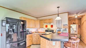 A modern kitchen with wooden cabinets, a stainless steel refrigerator, and a central island with bar stools. - 5 Mi to Downtown Morganton: Cabin on Horse Farm (Morganton)