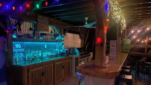 Un espace bar avec des meubles en bois, un comptoir où sont exposées différentes bouteilles et un panneau indiquant la présence d’une connexion Wi-Fi.