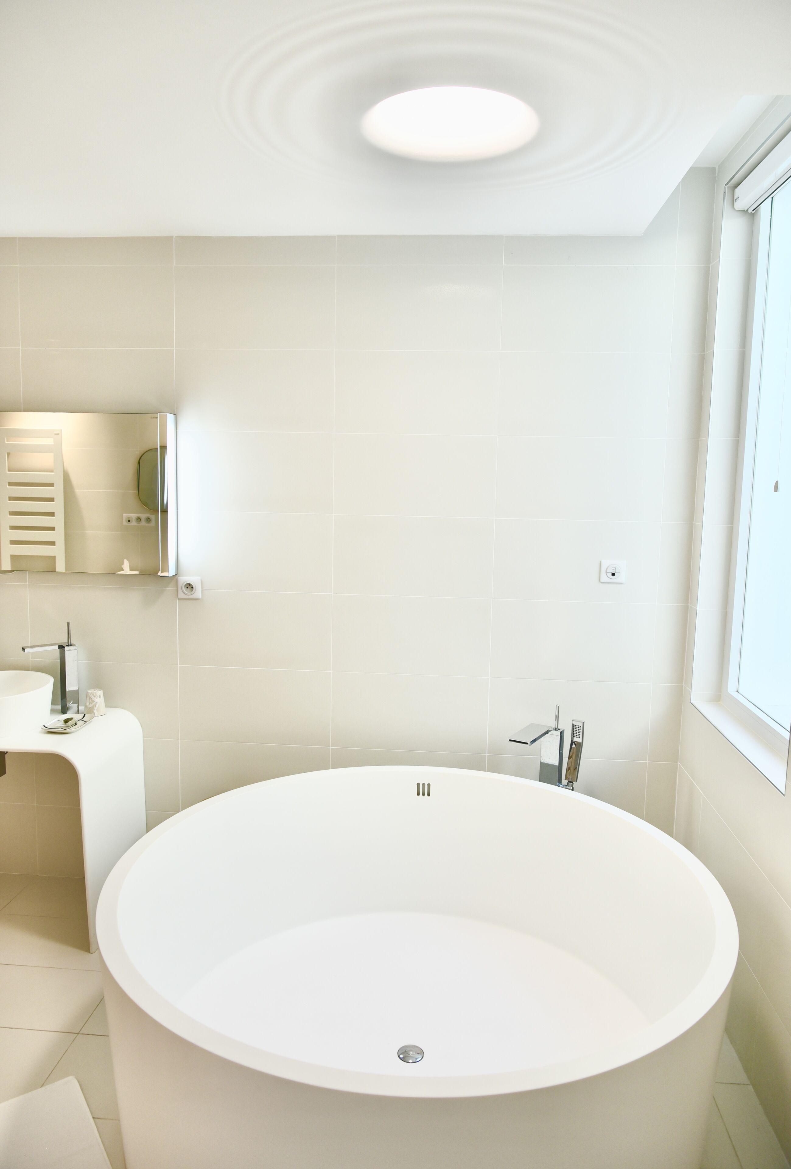 A modern bathroom with a freestanding bathtub, a sink, and a mirror.