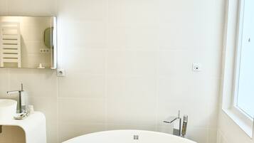 A modern bathroom with a freestanding bathtub, a sink, and a mirror.