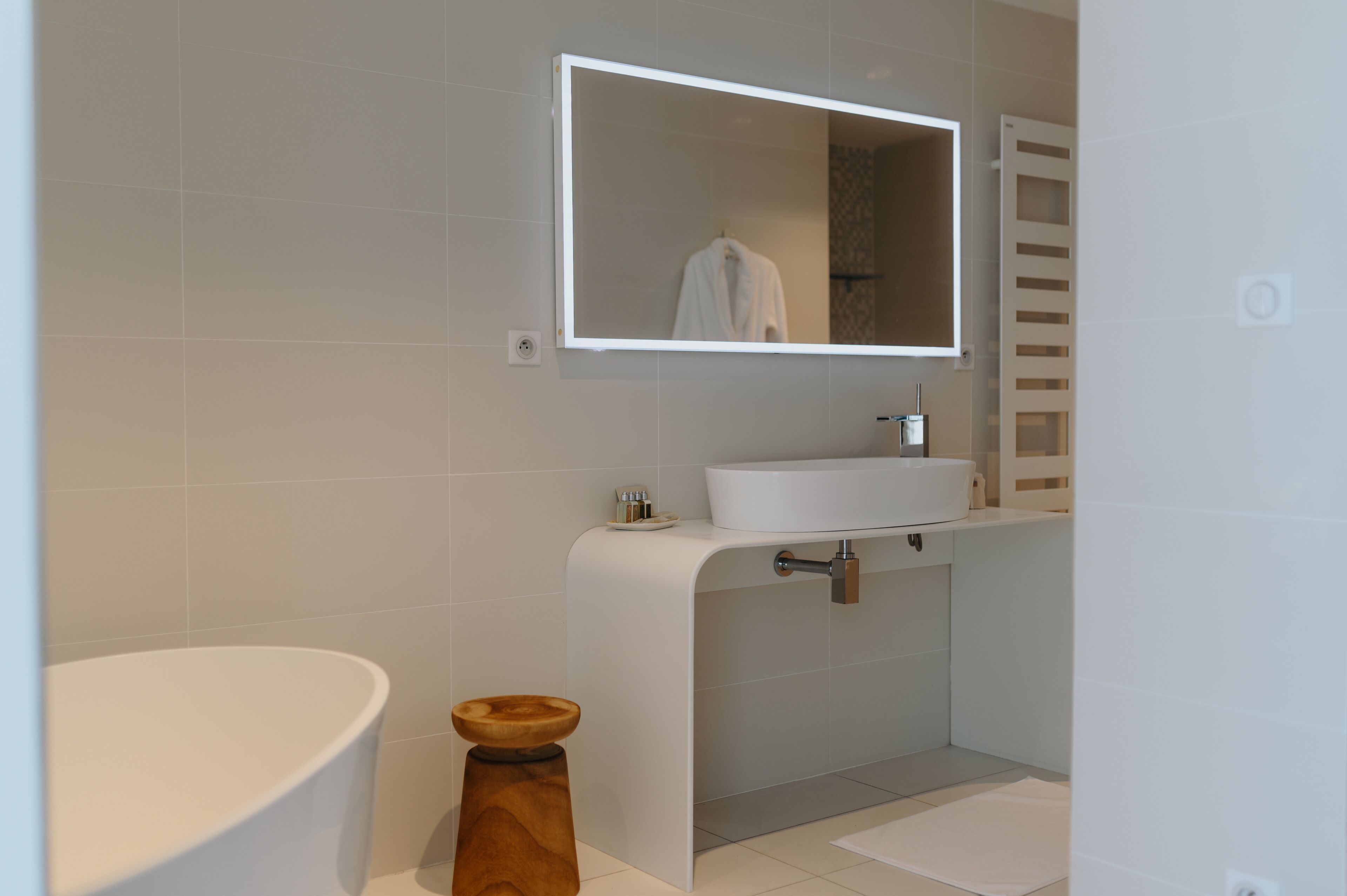 Un baño moderno con lavamanos, espejo y retrete blancos.