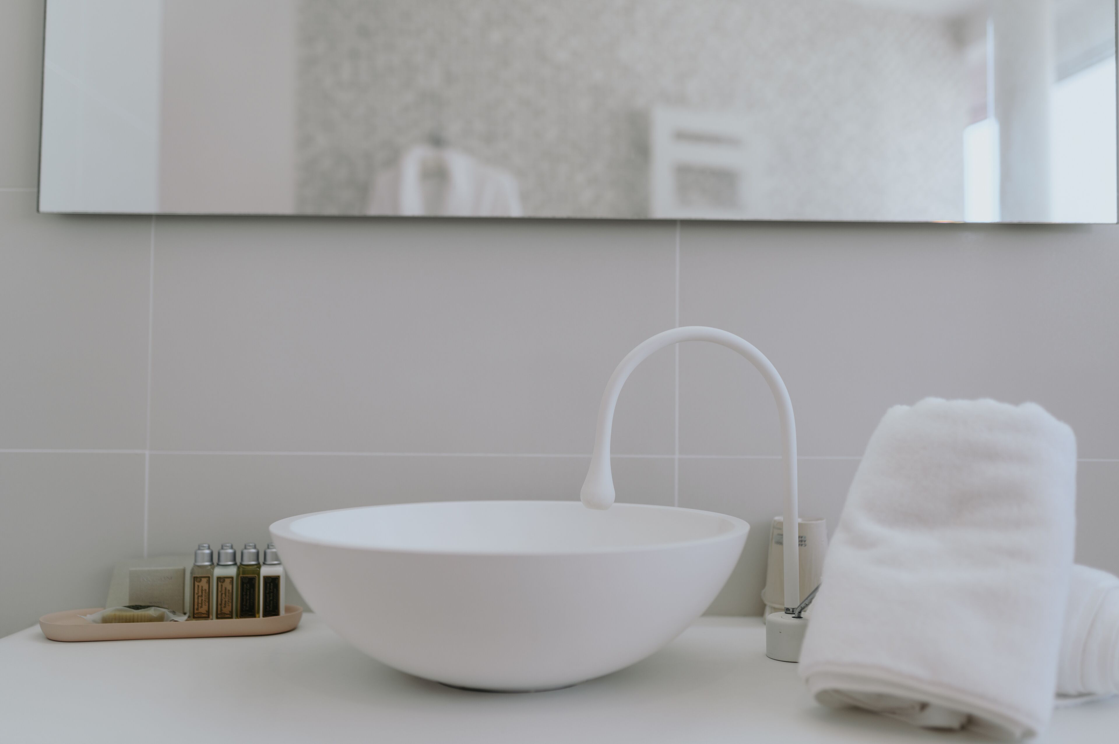 Une salle de bain moderne avec un lavabo sur colonne blanc, une serviette et des articles de toilette disposés sur un plateau.