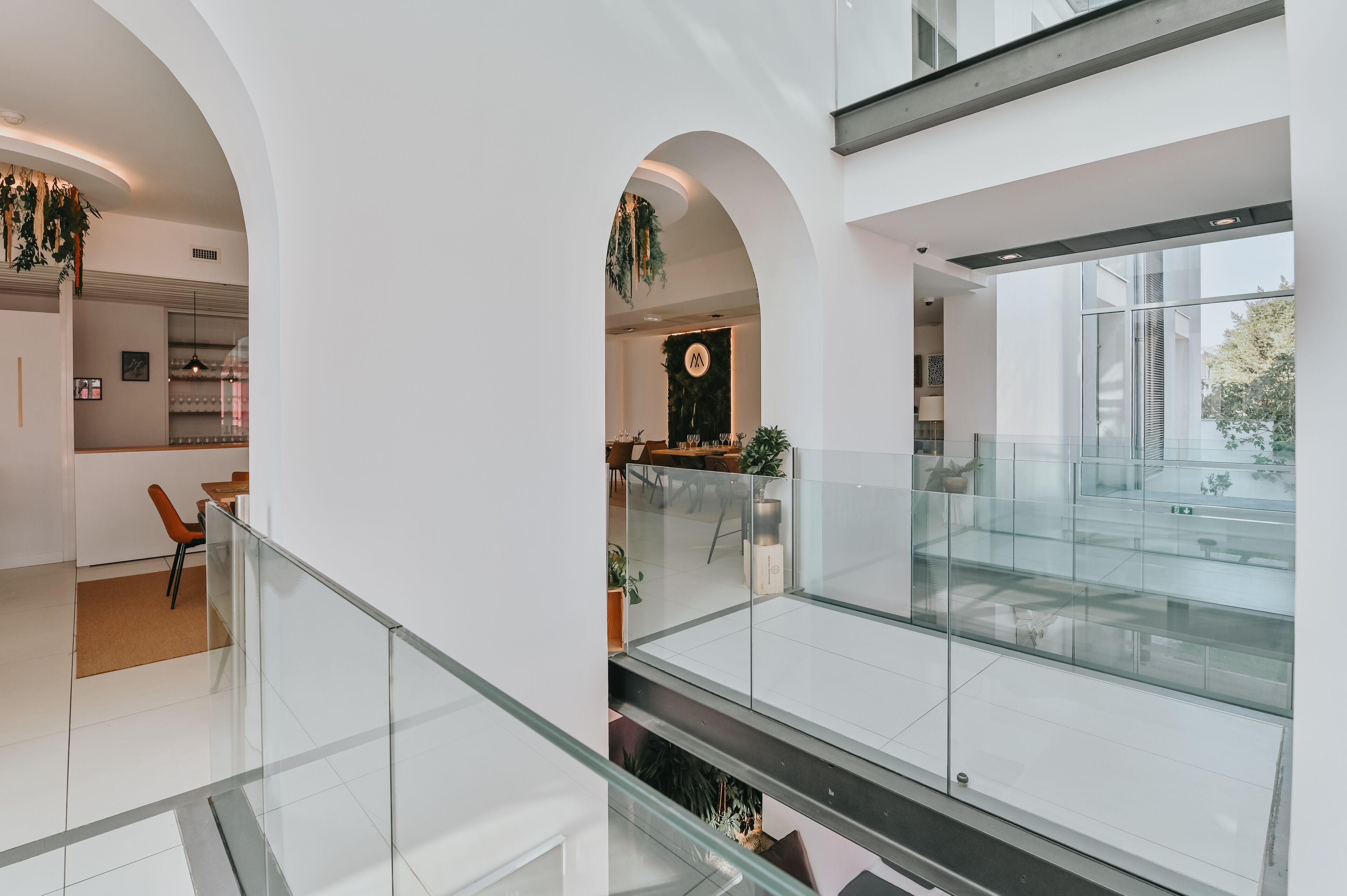 A modern interior with a glass railing, a kitchen area, and a dining space.