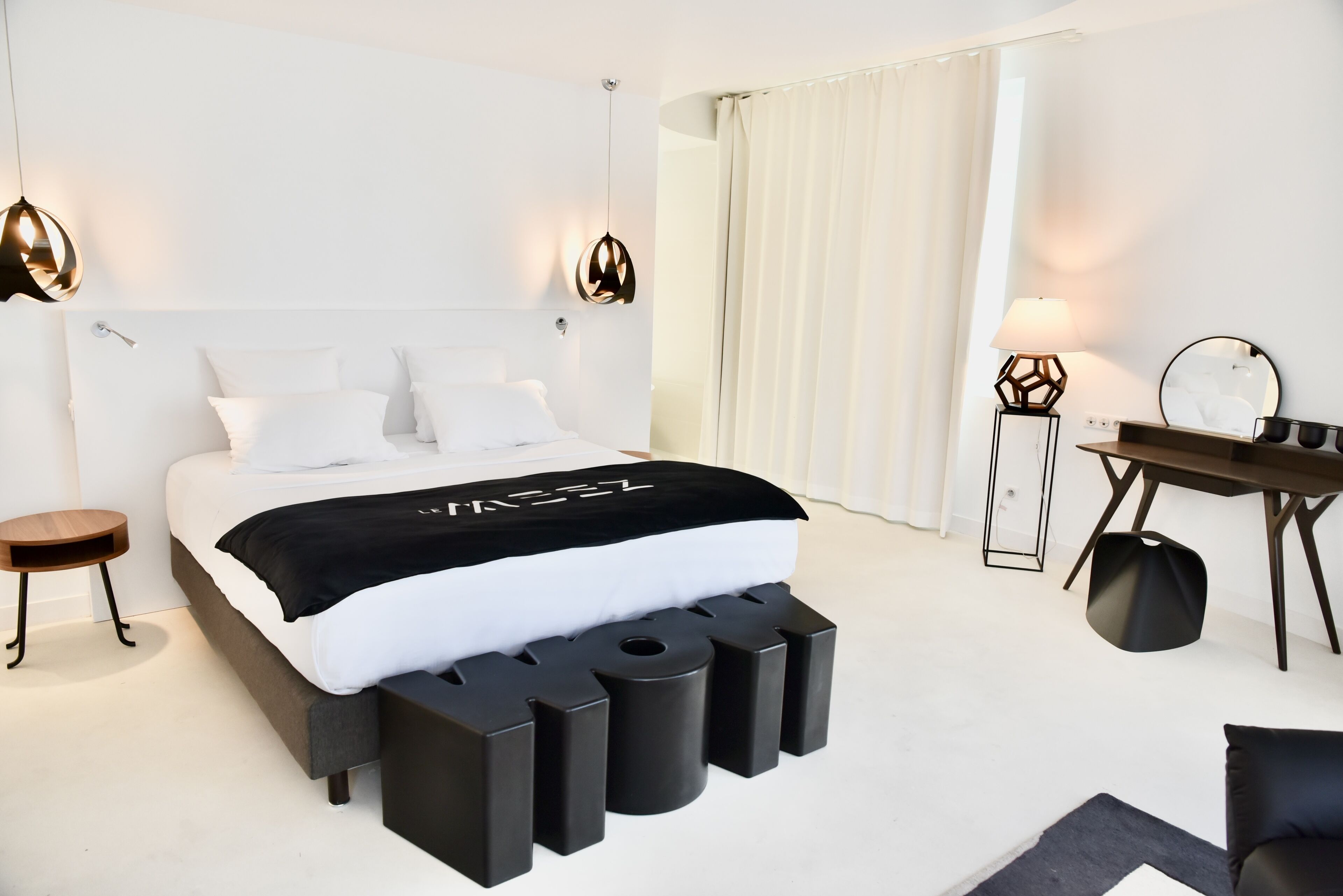 Una habitación de hotel moderna con una cama grande, mesitas de noche, un escritorio y una silla.