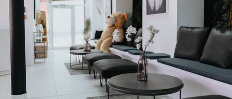 A modern living room with a sofa, ottomans, a coffee table, and a teddy bear.