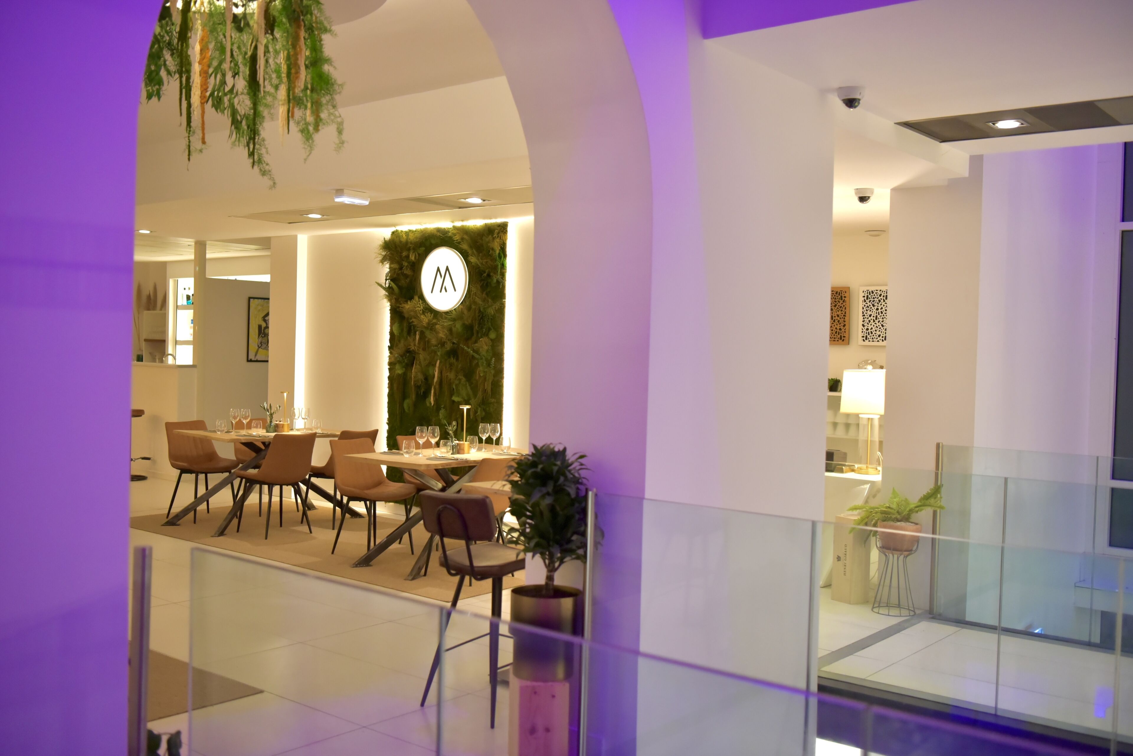 A modern dining area with a round table, chairs, and a wall-mounted logo.