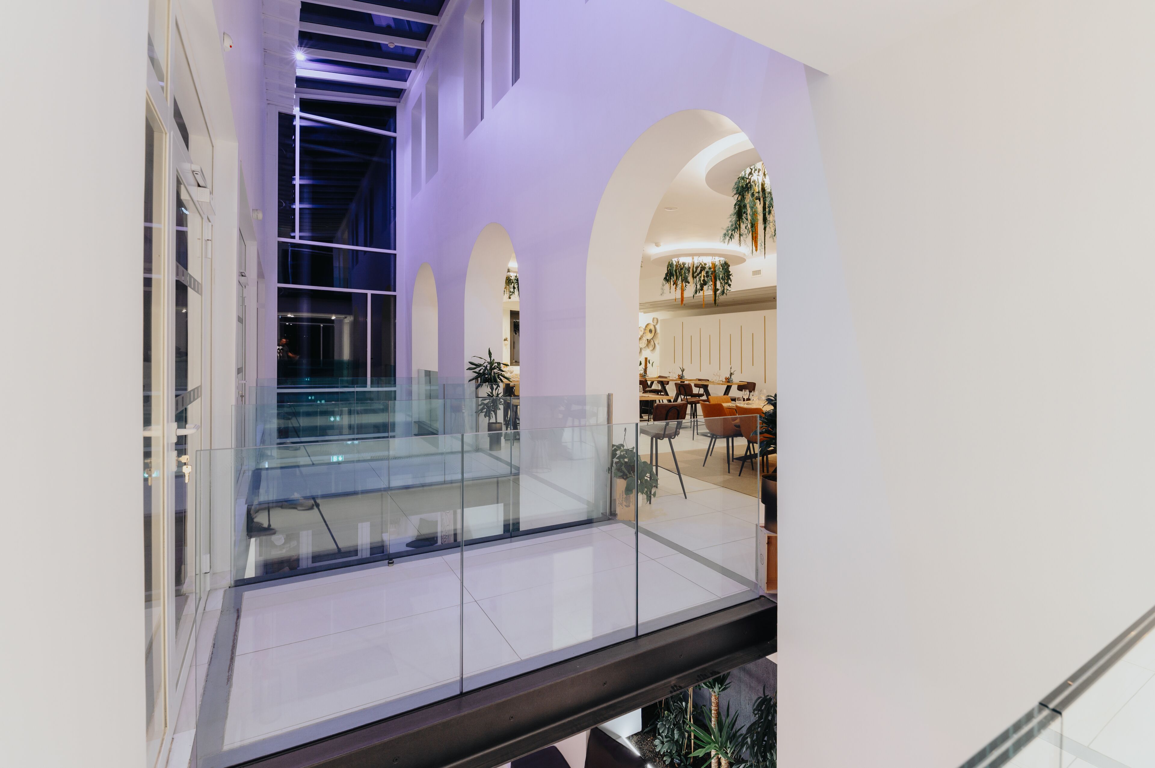 A modern interior with a glass railing, white walls, and a mezzanine level.