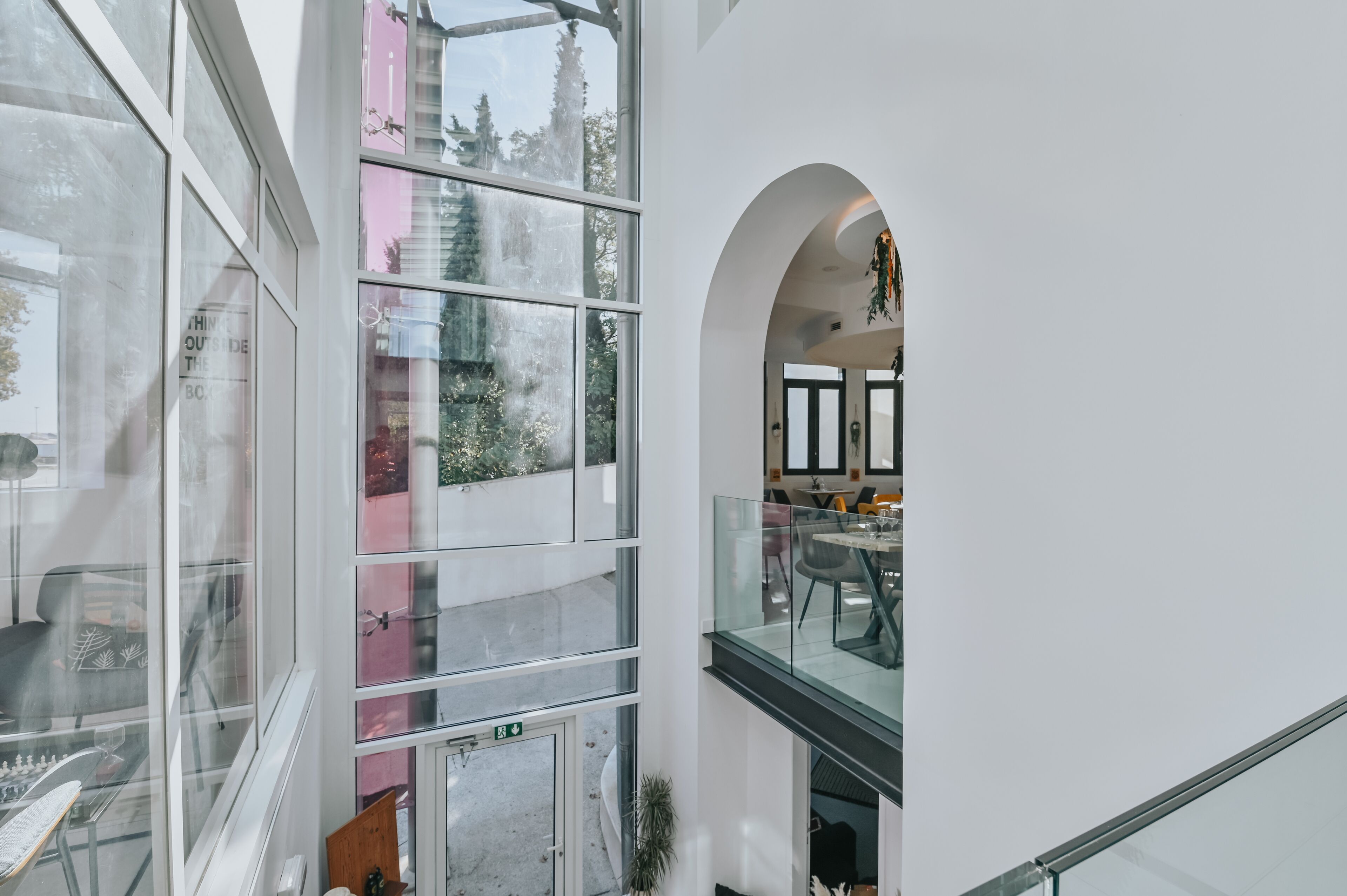A modern interior with large windows, a glass railing, and a view of trees outside.
