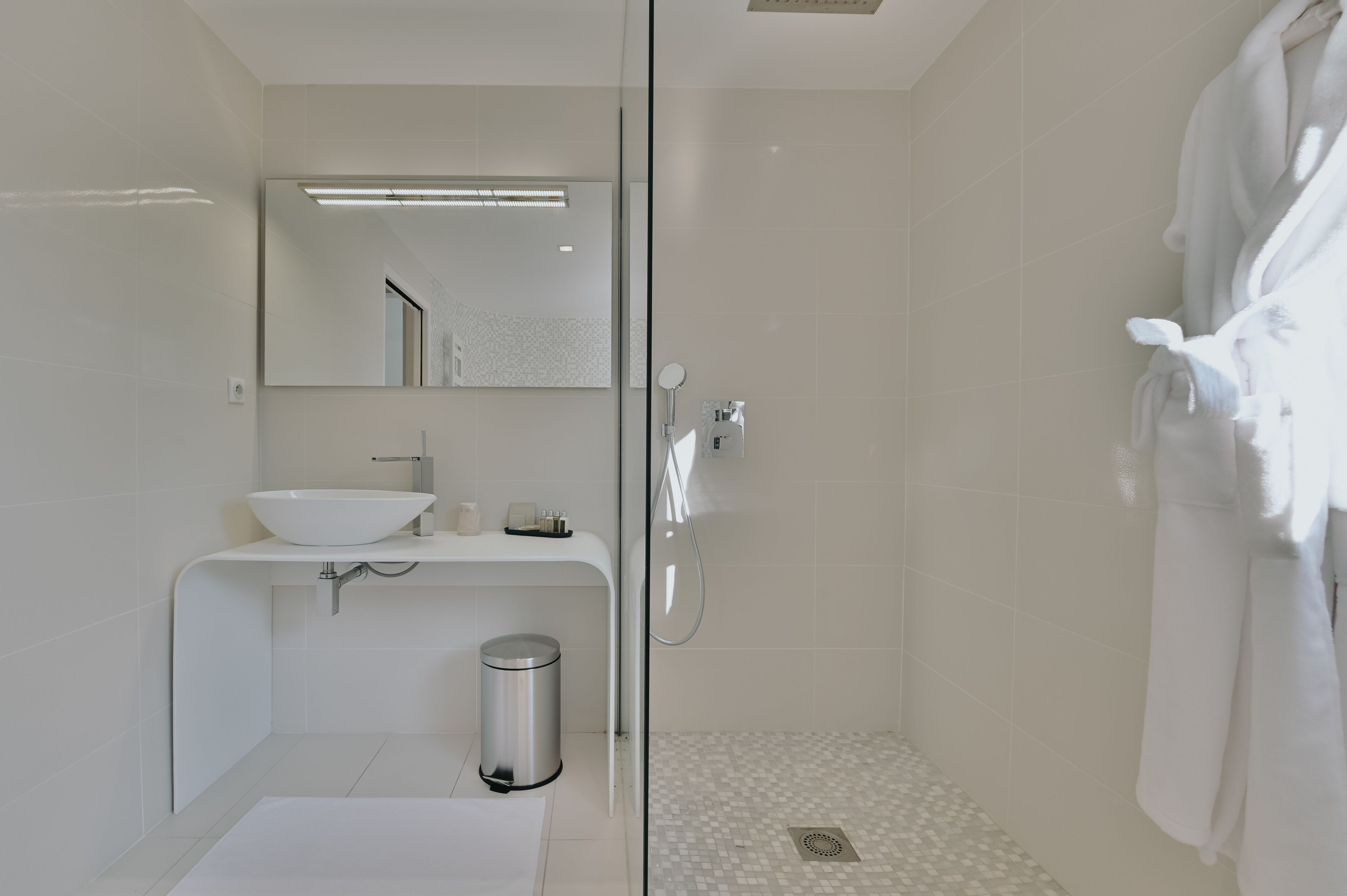 Un baño moderno con cabina de ducha de vidrio, un lavabo blanco y un espejo sobre él.