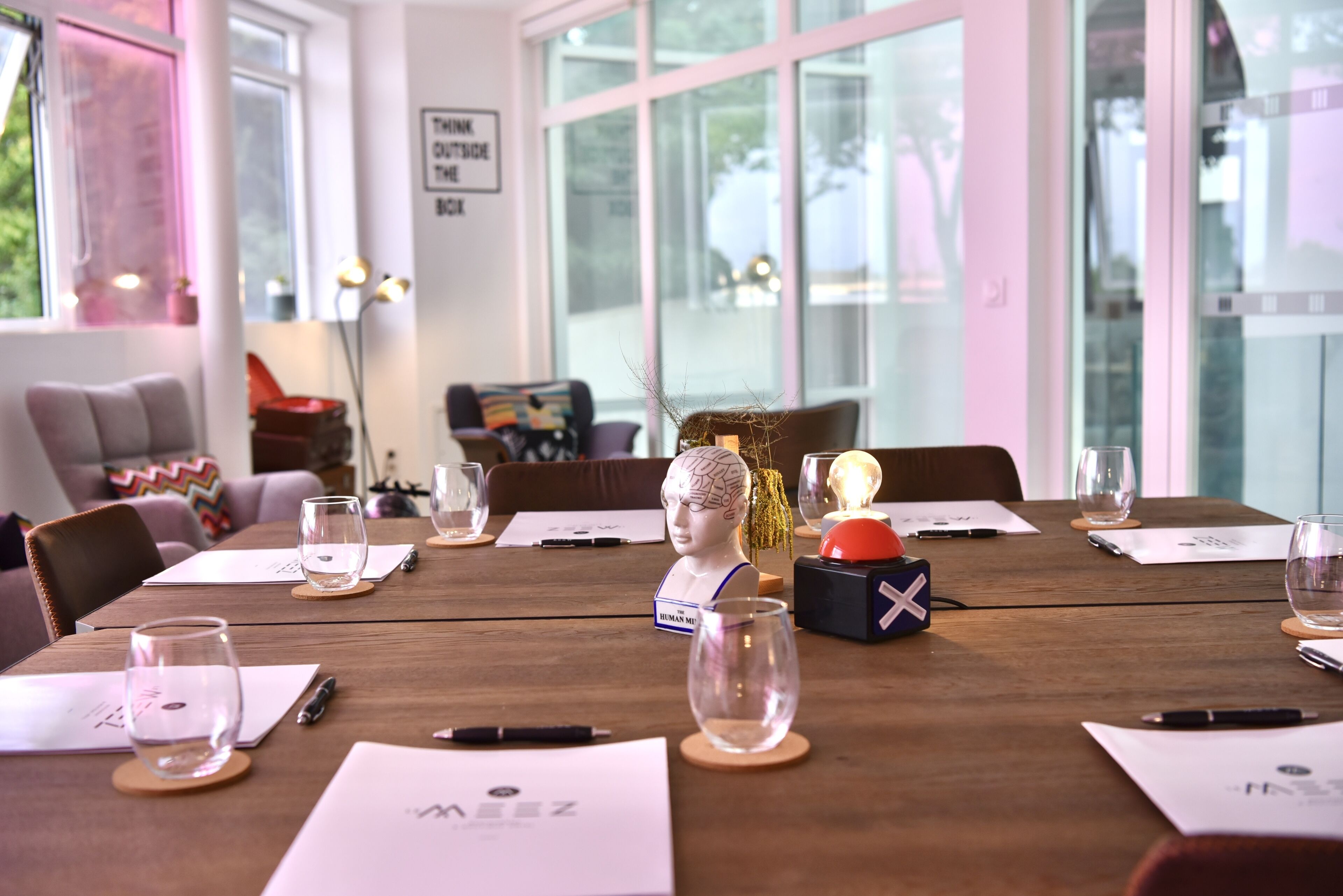 Un salón de conferencias con una mesa de madera, tarjetas de identificación y una escultura de busto.