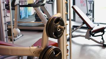 Un gimnasio con equipo de ejercicio, que incluye una prensa de banca y una cinta de correr.