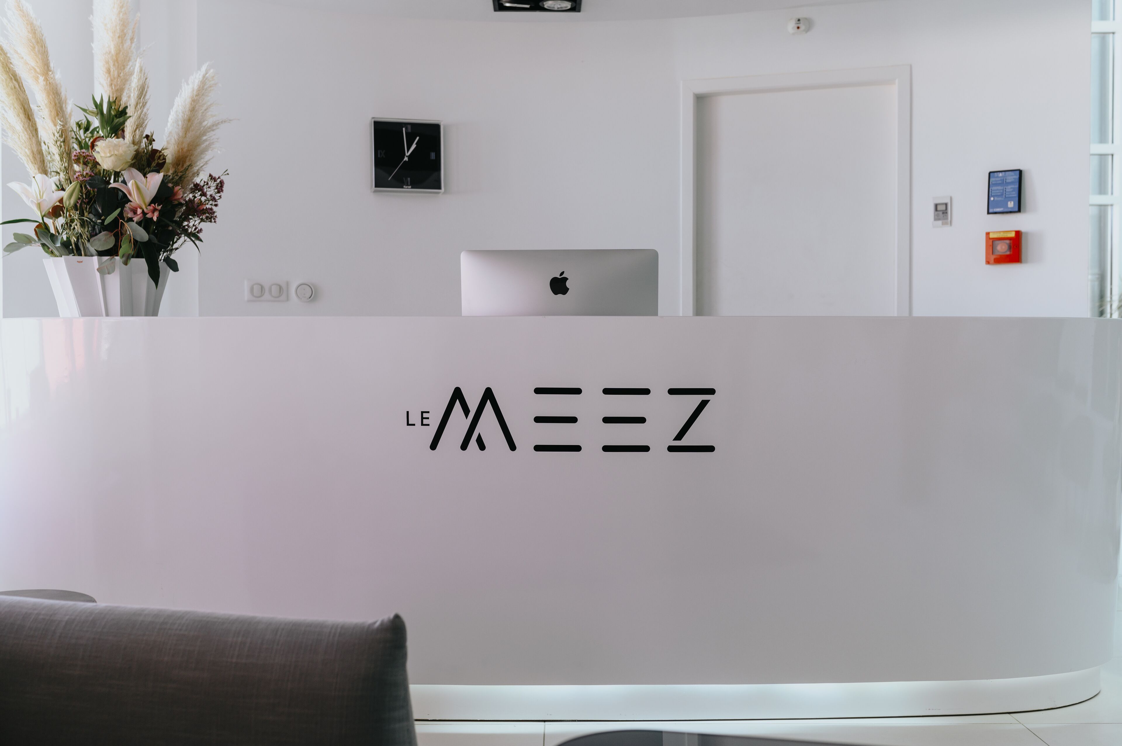 A reception desk with a laptop, a clock, and a wall-mounted sign.