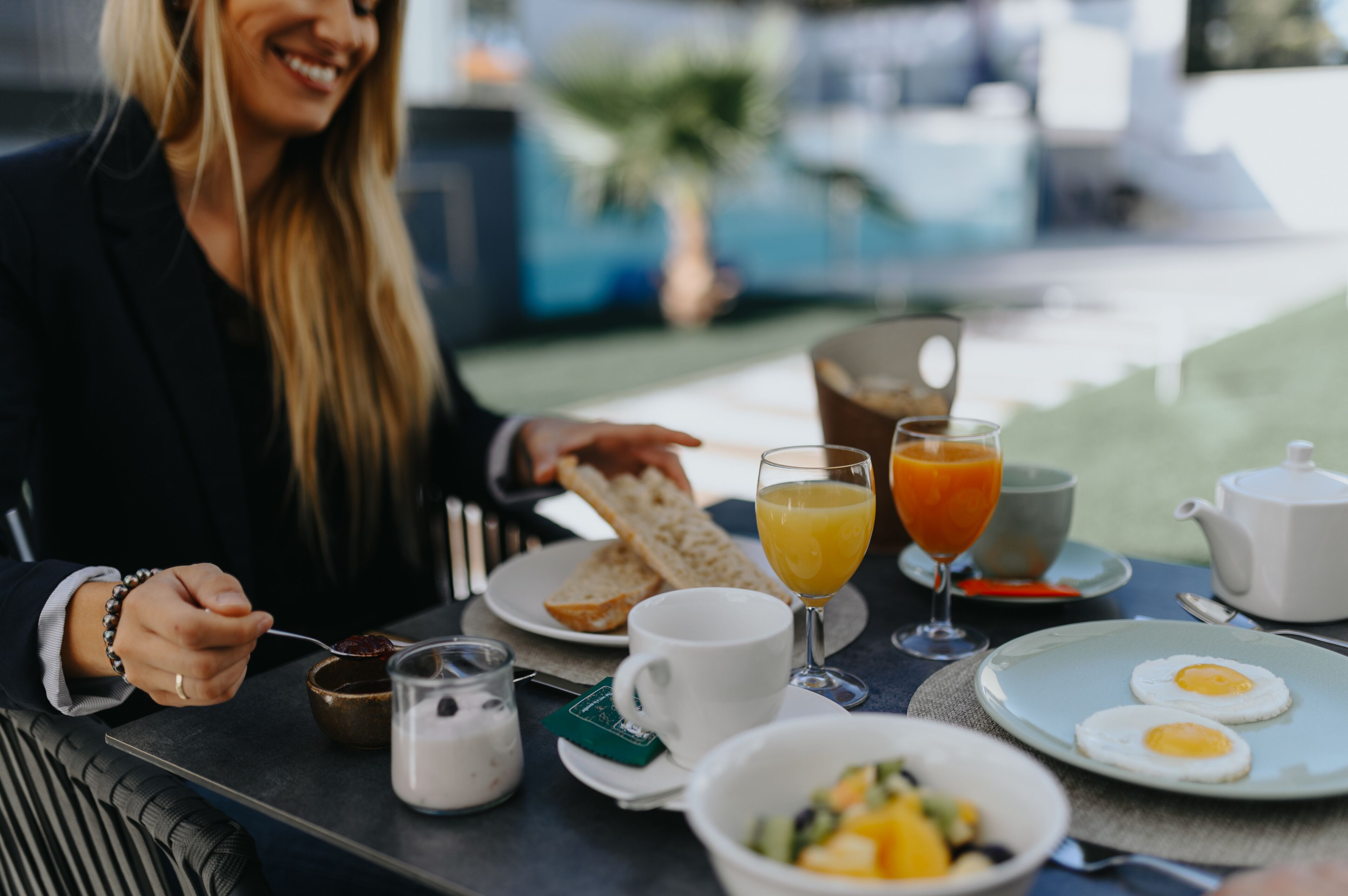 A breakfast table with toast, orange juice, eggs, and a coffee pot.