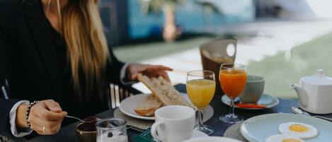 A breakfast table with toast, orange juice, eggs, and a coffee pot.