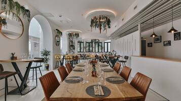 A modern dining area with a long wooden table set for six, surrounded by brown chairs.