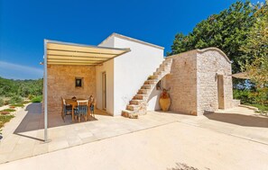 A stone house with a covered patio, a dining area, and a staircase leading to a second level. - Cozy home in Cisternino (Cisternino)