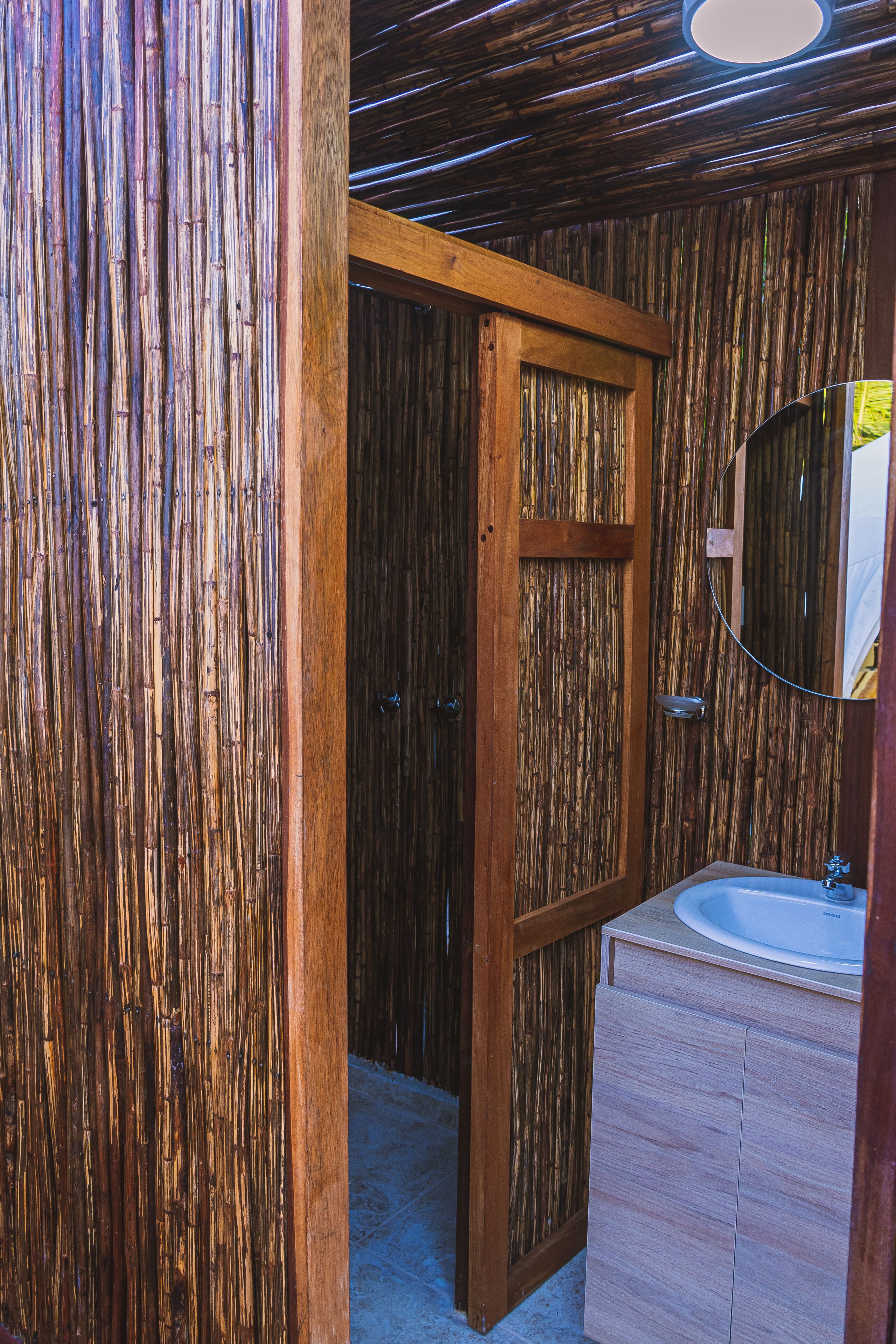A bathroom with a wooden door, a mirror, and a sink.