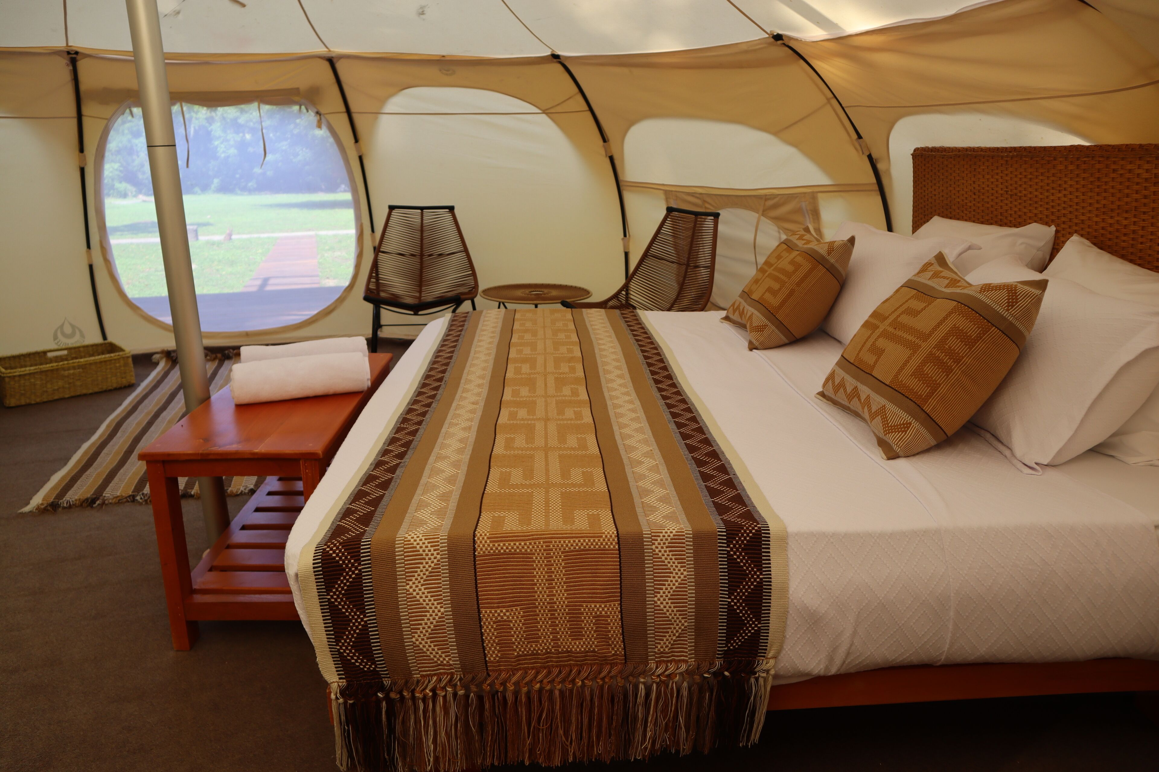 A tent with a bed, a table, and a window.