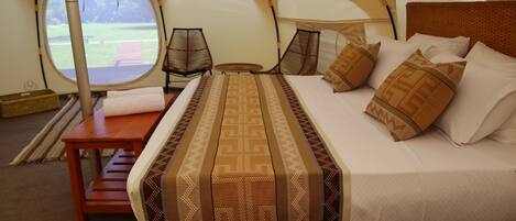 A tent with a bed, a table, and a window.