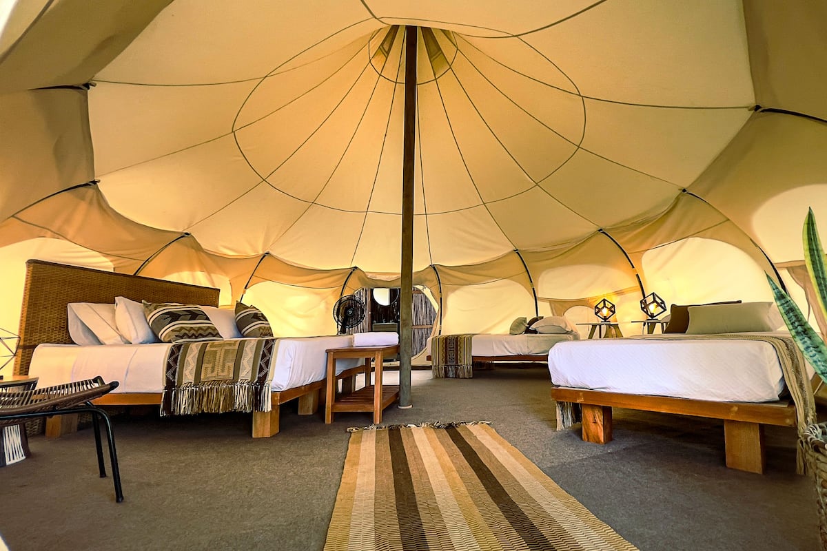 A tent with two beds, a table, and a chair.