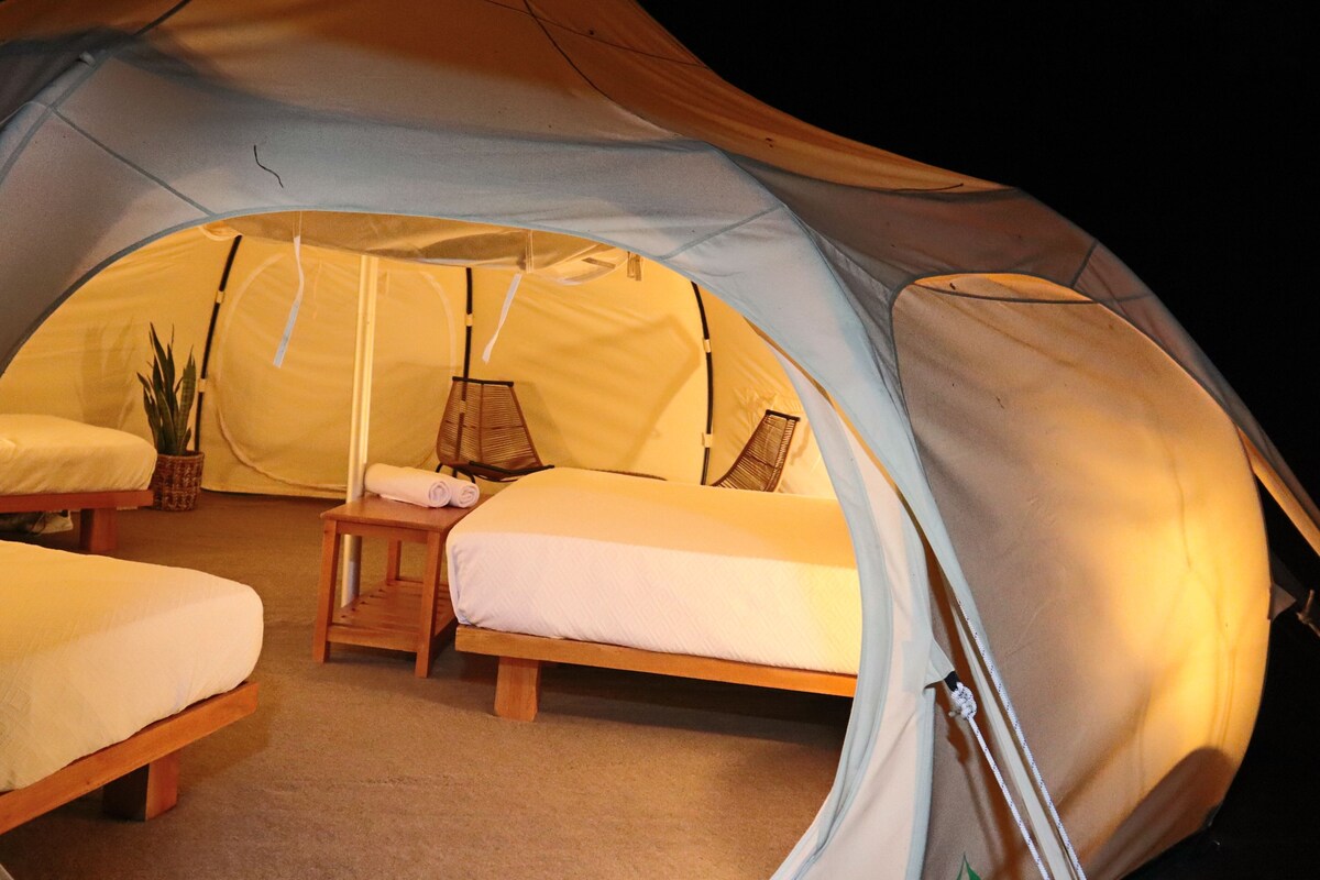 Una carpa con dos camas, una mesa y una lámpara.