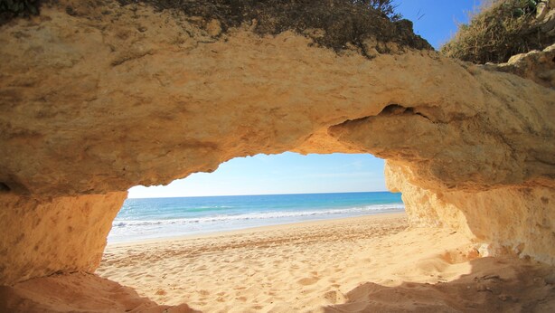 A beach with a natural rock arch formation.