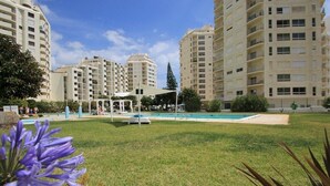 A residential area with high-rise buildings, a swimming pool, and a grassy lawn.