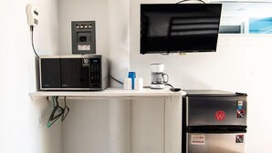 Una kitchenette compacta con microondas, cafetera y refrigerador.