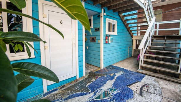 Un edificio azul con una puerta blanca, una escalera y un suelo de mosaico.