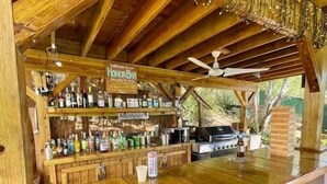 A wooden bar area with a sign reading "Honor Bar," a counter with various bottles, and a grill in the background. - Seahorse:1 Queen Bed (East End)