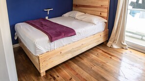 A wooden bed in a room with blue walls and a wooden floor. - Moon Apartments  First Floor (#3) (Isla de Utila)