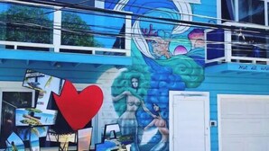 A building with a mural featuring marine life and a heart symbol. - Moon Apartments  First Floor (#3) (Isla de Utila)