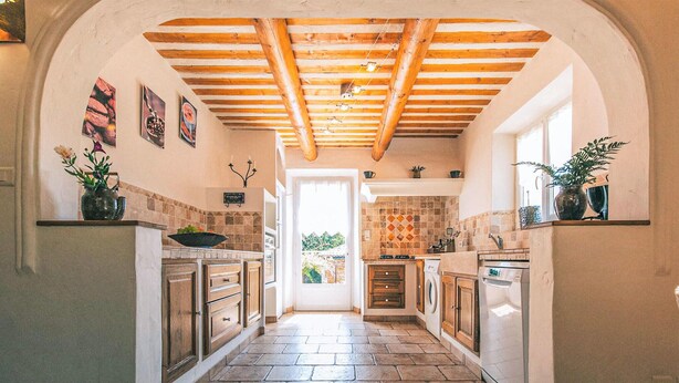 A kitchen with stone flooring, wooden cabinets, and a tiled backsplash. - Amazing home in Lioux (Lioux)