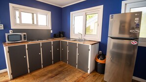 Eine kompakte Küche mit Mikrowelle, Kaffeemaschine und Edelstahlkühlschrank.