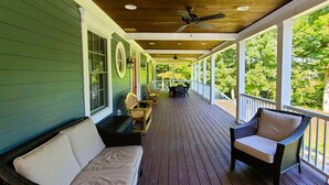 A covered porch with a wooden floor, green walls, wicker furniture, and a view of trees. - Oversized Country house, Quiet Retreat & Gathering space ~NEW !!!  (Ulster Park)