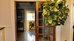 A hallway with a wooden floor, a potted plant, and a door leading to a dining area. - Oversized Country house, Quiet Retreat & Gathering space ~NEW !!!  (Ulster Park)