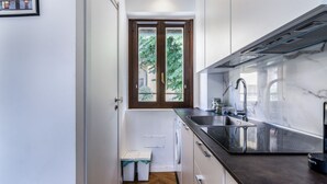 Une cuisine moderne équipée d’un lave-vaisselle encastré, d’un évier et d’une fenêtre donnant sur un espace verdoyant.