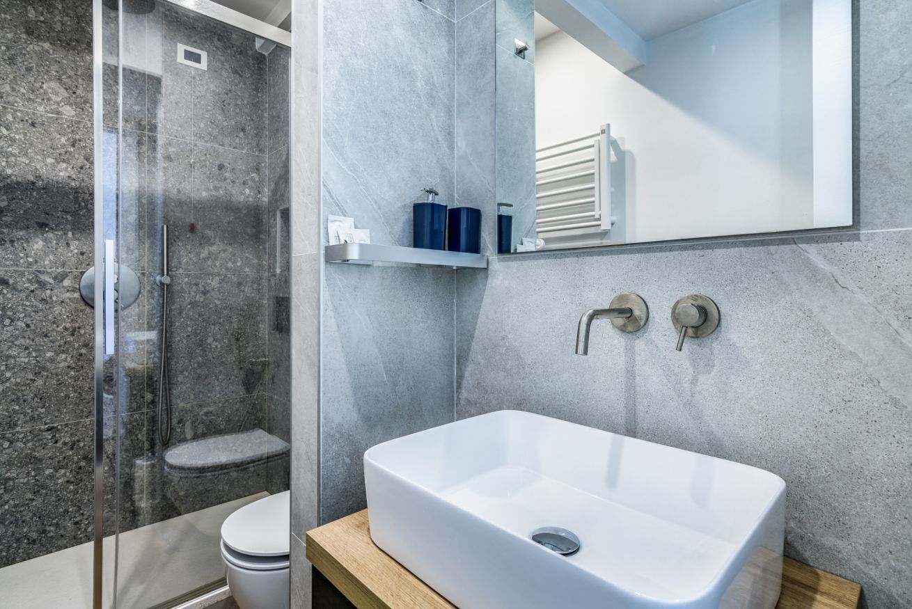 Ein modernes Badezimmer mit einer Duschkabine, einem weißen Waschbecken und einem Spiegel darüber.