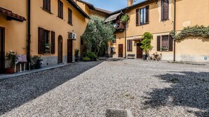 Une cour intérieure avec des bâtiments, un sol recouvert de gravier et des plantes en pot.