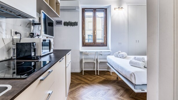 Une cuisine compacte dotée d’appareils électroménagers modernes, un coin repas et un lit avec des serviettes.