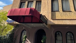 A hotel with a red awning, multiple balconies, and a sign reading "HOTELS". - G Hotels (Skopje)