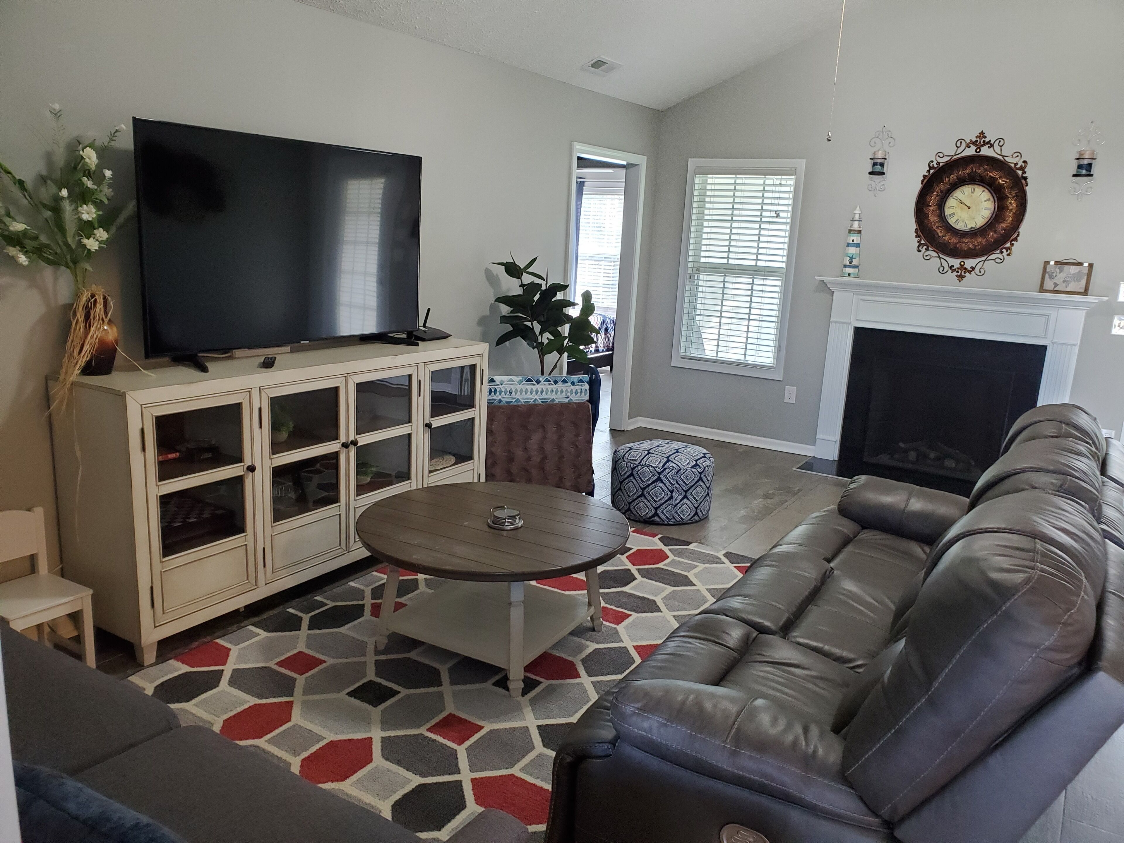 A living room with a TV, a cabinet, a sofa, a coffee table, and a fireplace.