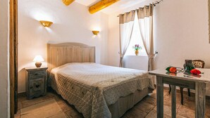 A bedroom with a bed, bedside table, lamp, and a small table with a vase and a rose. - 2 bedroom gorgeous home in Roussillon (Roussillon)