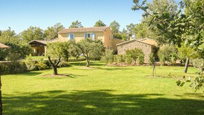 A large house with a tiled roof, surrounded by a well-maintained lawn and several trees. - 2 bedroom gorgeous home in Roussillon (Roussillon)