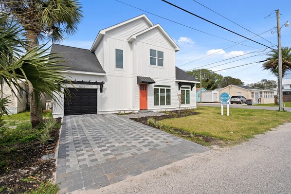 A two-story house with a paved driveway, a red door, and a garage. - Brand NEW Expansive Coastal Home w/ Custom Furnishings Sleeps 15 (Panama City Beach)
