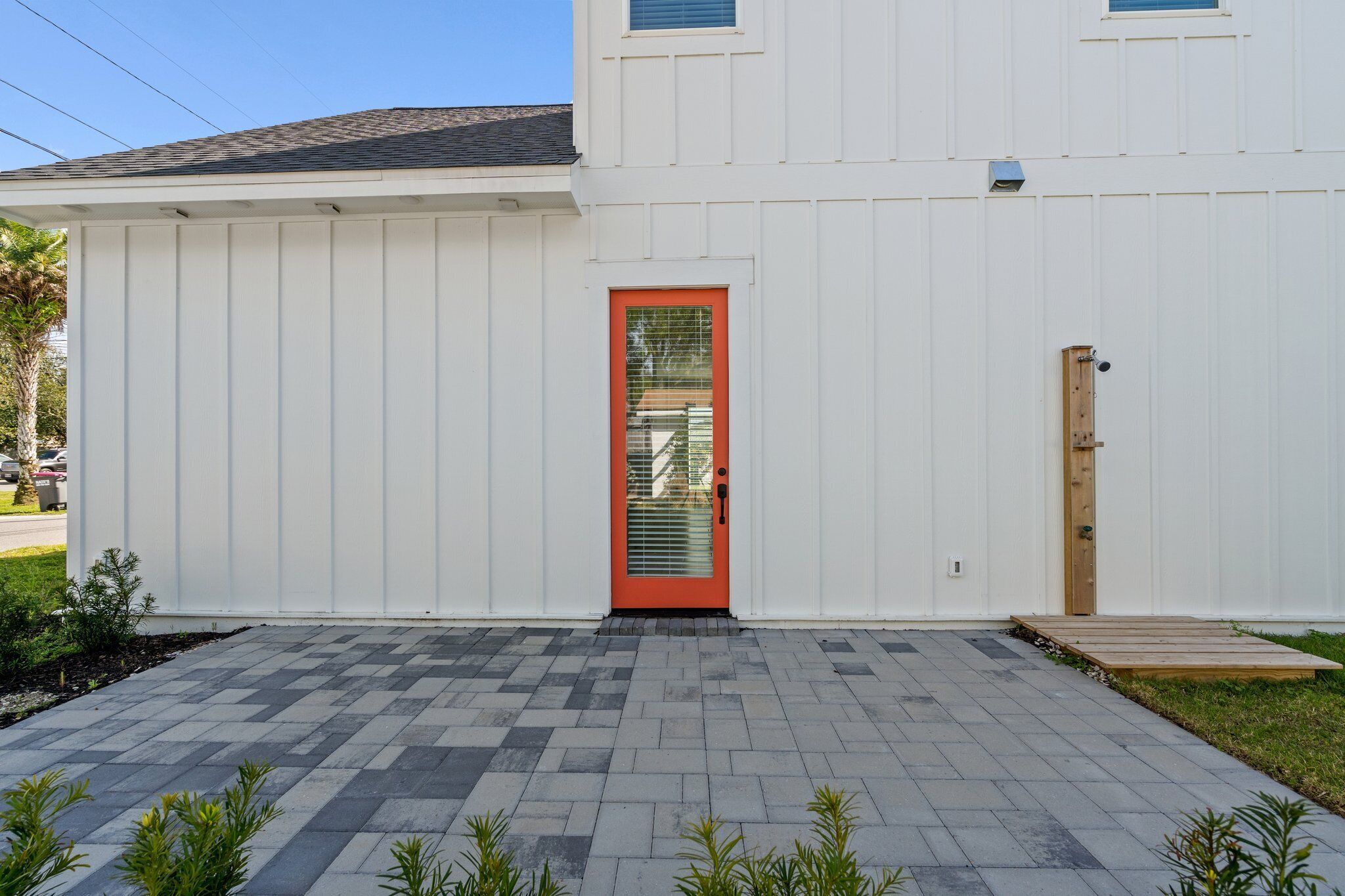 Un bâtiment blanc avec une porte rouge et une petite porte en bois sur la droite.