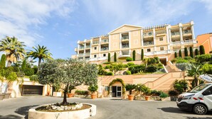A multi-story hotel with balconies, a central entrance, and a parking area with a car. - Awesome apartment in Cannes with swimming pool (Cannes)