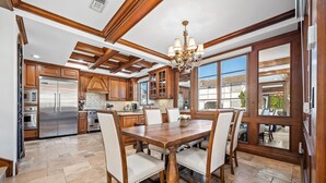 Una cocina amplia con armarios de madera, una mesa de comedor grande y una araña.