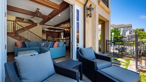 Un patio amplio con muebles de mimbre, una escalera que lleva a un nivel superior y vistas de casas vecinas.
