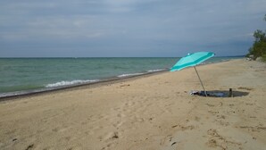 A beach with a single blue umbrella on the sand.